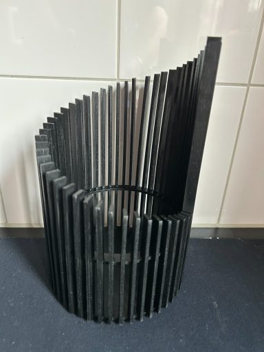 Zwart metalen bloemenvaas met verticale ribbels en een golvende bovenrand.